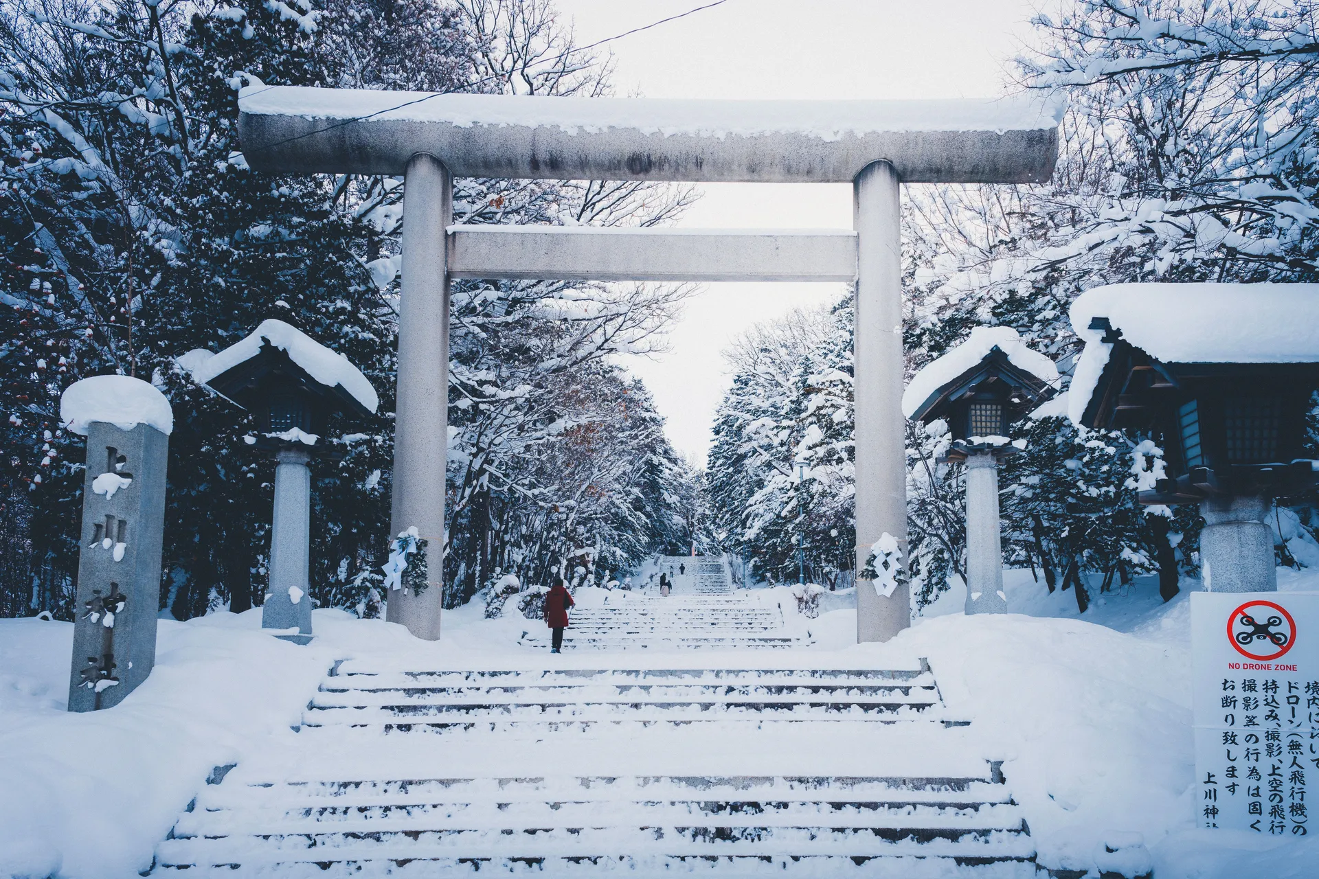 Snow-covered torii gate and stone steps on a winter shrine approach in Japan
